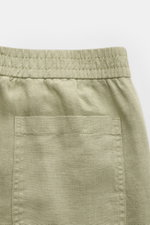 Close-up image from the back top view of 04651/ A trip in a bag Leinen-Jogpants 'Linen Pants' salbei, showing elastic waistband, pure linen fabric with typical texture, and a patch pocket, perfect for warm days with tapered fit, regular thigh width, ankle