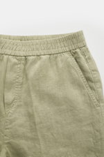 Close-up front view of 04651/ A trip in a bag Leinen-Jogpants 'Linen Pants' salbei, showing elastic waistband, pure linen fabric with typical texture, tapered fit, regular thigh width, ankle length, straight cut, small woven label, French pockets, and pat