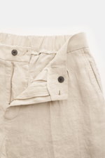 Close-up front view of 04651/ A trip in a bag Linen jogger pants 'Linen Pants' beige showing zipper, button, and partially elasticated waistband.

<p>Perfect for warm days: These linen jogger pants by 04651/ A TRIP IN A BAG are the ideal summer essential 