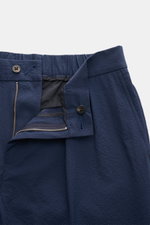 Close-up front view of the 04651/ A trip in a bag Seersucker trousers 'Technical Seersucker' navy, showing zip and waist button. Seersucker made of microfibre with fine, typical material texture and robust fabric, tapered fit, regular thigh width, ankle l