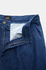 A.P.C. Baumwollhose 'Ricky' dunkelblau, nah aus schräger Perspektive mit offenem Zip Fly, hohem Bund und französischen Taschen aus Baumwoll-Denim.