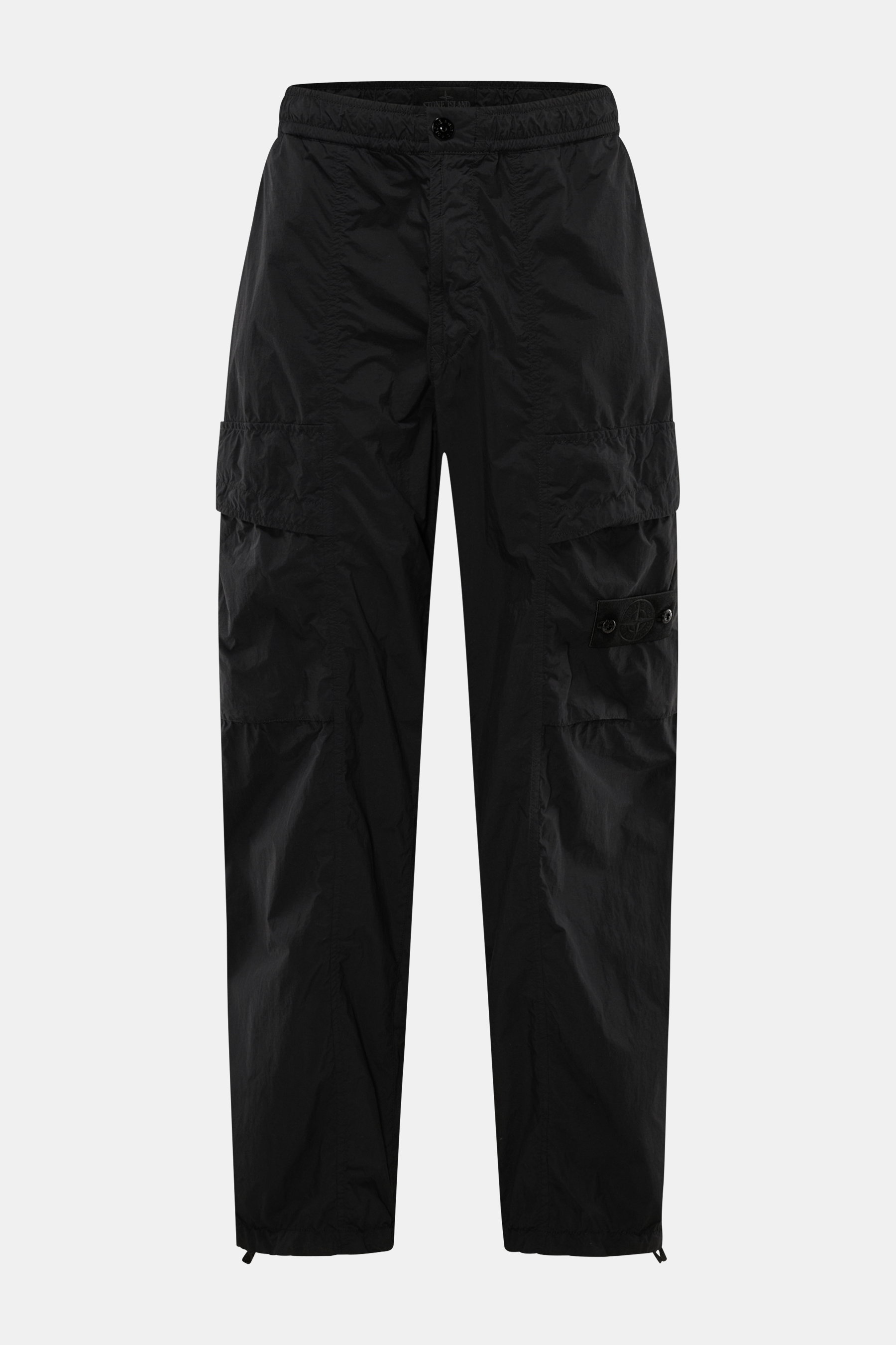 Frontale Nahaufnahme der Stone Island Cargohose 'Ghost Piece' schwarz aus leichter Microfaser mit Loose Fit, geradem Schnitt, elastischem Bund, Cargo- und Gesäßtaschen, tonalem Kompass-Badge und regulierbarer Saumweite.