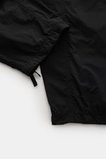 Black close-up detail of Stone Island Cargo Pants 'Ghost Piece' Black hem and drawstring, photographed from above, lightweight microfiber, smooth touch, garment dyed, loose fit, straight cut, elastic waistband with drawstring, French pockets, cargo pocket
