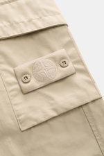 Close-up side view of Stone Island Cargo Pants 'Ghost Piece' sand in robust cotton poplin with tonal compass badge on thigh pocket.

Description: <p>Monochrome all-rounder for casual looks: these cargo pants made of robust cotton poplin from STONE ISLAND 