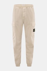 Stone Island Cargo Jogpants beige front view, elastic organic cotton, tapered fit, cargo pockets, zip fly, compass badge, elastic waistband and cuffs.