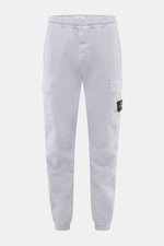 Front view of Stone Island Cargo Jogpants smoky blue, elastic organic cotton with stretch, tapered fit, zip fly, cargo and concealed zipper pockets, elastic waistband and leg cuffs, typical compass badge, darts at knees, back pocket with snap button.

Des