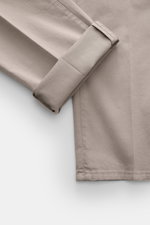 Close-up top view of folded Brunello Cucinelli Chinos 'Italian Fit' sand, showcasing twill elastic cotton fabric, soft feel, and tapered cut.