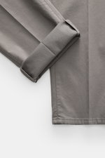 Close-up top-down view of folded grey Brunello Cucinelli Chinos 'Italian Fit' showcasing soft, elastic twill fabric and fine stitching.