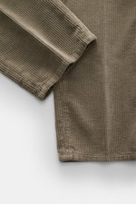 Brunello Cucinelli Corduroy pants sage close-up from above showing pure cotton fabric with soft feel, single pleat, and slim tapering detail.