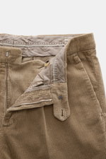 Brunello Cucinelli Light brown corduroy pants shown from a close-up front view with open zipper, waistband buttons, single pleat, and French pockets, made of pure cotton with a soft feel, garment dyed, regular fit, very slim tapering, and welt pockets at 