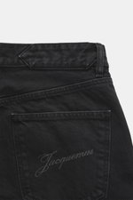 Jacquemus Jeans schwarz aus reiner Baumwolle, Regular Fit, gerader Schnitt, Button Fly, Five-Pocket-Stil, innenliegendes Weblabel, Detail Rückseite nah.