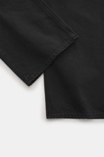 Nahaufnahme der Jacquemus Jeans schwarz, fotografiert aus seitlicher Perspektive, aus Denim aus reiner Baumwolle, Regular Fit, gerader Schnitt, Button Fly, Five-Pocket-Stil, innenliegendes Weblabel, leicht griffige Haptik.