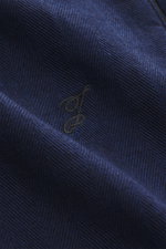 Nahaufnahme von dunkelblauem Jacquemus Denim-Jogpants Stoff mit weichem Griff, Denim aus reiner Baumwolle, elastischem Bund, Button Fly, geradem Schnitt und innenliegendem Weblabel.