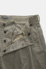 Close-up front view of Massimo Osti Studio Trousers grey green, showing button fly, double waistband pleat, small watch pocket, piped pockets, back pockets with flap and button, made of cotton and microfiber with smooth touch, loose fit, straight cut, and