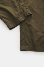 Close-up view of C.P. Company Cargo pants olive showing high-quality microfiber fabric, soft feel, tapered fit, straight short cut, zipper and waistband button, French pockets, practical cargo pockets, back pocket with flap, and label-typical lens detail.