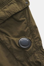 Close-up top-down view of C.P. Company Cargo pants olive, highlighting high-quality microfiber, soft feel, tapered fit, straight short cut, zipper and waistband button, French pockets, practical cargo pockets, back pocket with flap, and label-typical lens