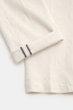 Close-up top view of the cuff of Mason's Chino 'Torinostyle' cream trousers showing soft-touch fabric made of modal, cotton, and microfiber, slim tapered fit, with stitched detail and typical metal initial. Features zipper and waistband buttons, French po