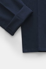 Nahaufnahme der Dondup Chino 'Gaubert' navy aus elastischer Baumwolle in Slim Fit, schmal geschnittene Wade, Reißverschluss, Slide Button, französische Taschen, Gesäßtaschen mit Knopf und typischem Metall-Initial, fotografiert aus seitlicher Perspektive.
