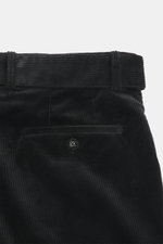 Close-up rear view of Officine Générale Corduroy pants 'Hoche' black, showing soft, slightly elastic cotton corduroy fabric, waistband with belt loops, and back pocket with button for a modern tapered fit. Parisian casualness with a modern claim: OFFICINE