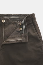 Nahaufnahme aus schräger Perspektive der geöffneten Taille der GTA Baumwollhose 'Davide' dunkelbraun aus elastischem Baumwoll-Twill mit Reißverschluss, Bundknopf, innenliegendem elastischem Band und feinem Logo-Detail.