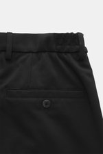 Nahaufnahme von der Rückseite der schwarzen GTA Jersey-Hose 'Dennis' mit elastischem Bund, fixiertem Saumaufschlag, französischen Taschen, Reißverschluss, Bundknopf und kleinem Logo-Detail. Jersey aus Viskose und Microfaser, elastisch, glatter Griff, Tape