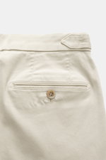 Back view close-up of GTA Chino 'Herrick' cream pants showing elastic cotton fabric, soft touch, regular fit, low waist height, zipper and waistband button, elastic insert in waistband, side adjuster, double waistband pleat, French pockets, and back pocke