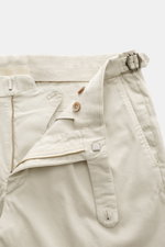 Close-up front view of GTA Chino 'Herrick' cream pants showing elastic cotton fabric, soft touch, regular fit, low waist height, zipper and waistband button, elastic insert in waistband, side adjuster, double waistband pleat, French pockets, and back pock