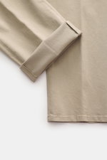 Close-up top-down view of the folded leg of GTA Chino 'Herrick' beige trousers, showcasing elastic cotton, soft touch, regular fit, low rise, zipper and waistband button, elastic insert in waistband, side adjuster, double waistband pleat, French pockets, 