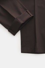 Nahaufnahme der dunkelbraunen Hiltl Baumwollhose 'Parma' aus Satin-Baumwolle, leicht elastisch, Regular Fit, schmal zulaufend, mit Zip Fly, Bundhaken, französischen und Knopf-Gesäßtaschen, glattem Griff, von oben fotografiert.
