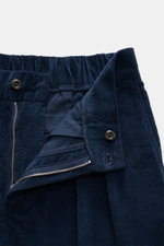 Nahaufnahme der geöffneten Bundpartie einer dunkelblauen 04651/ A trip in a bag Cordhose, aus softem Baumwoll-Cord mit Reißverschluss, Bundknopf und teilelastischem Bund.