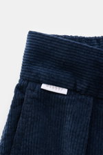 04651/ A trip in a bag Cordhose dunkelgrün im Detail aus Baumwoll-Cord mit Seersucker-Rückseite, Nahaufnahme des Bunds mit Label und weichem Griff.