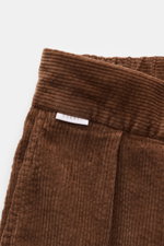 Brown cotton corduroy close-up of waistband and label, photographed from a top-front angle, 04651/ A trip in a bag Corduroy Pants navy.
