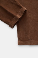 Brown corduroy fabric close-up showing folded cuff and texture from a top-down perspective, highlighting 04651/ A trip in a bag Corduroy Pants navy. These corduroy pants by 04651/ A TRIP IN A BAG are made of cotton corduroy with a seersucker backside, pro