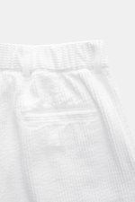 Close-up front view of 04651/ A trip in a bag Corduroy pants white, made of soft wide cotton corduroy with seersucker inside, showing waistband, pleats, side pockets, zipper, button, and fixed hem cuff, designed for comfort and casual style.