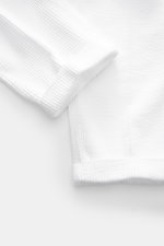 Close-up of the cuff and fabric texture of 04651/ A trip in a bag Corduroy pants white, made of soft wide cotton corduroy with seersucker backing, photographed from a top-down angle showing the detailed ribbed pattern and fixed hem cuff.