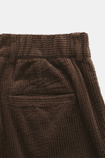 Detailaufnahme der taillierten 04651/ A trip in a bag Cordhose dunkelbraun aus breitem Baumwoll-Cord mit weichem Griff, doppelter Bundfalte und Leistentaschen, fotografiert von oben.