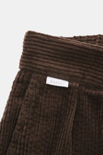 Nahaufnahme der Bundpartie der dunkelbraunen 04651/ A trip in a bag Cordhose aus breitem Baumwoll-Cord mit weichem Griff und Seersucker-Innenseite.