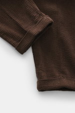 04651/ A trip in a bag Cordhose dunkelbraun, Detailaufnahme von unten schräg auf den fixierten Saumaufschlag aus softem Baumwoll-Cord mit Seersucker-Innenseite.