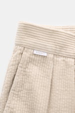 Close-up front view of beige corduroy fabric with label "04651/", highlighting the texture and waistband details of 04651/ A trip in a bag Cord Cargo Pants Dark Brown. Modern design, highest wearing comfort: the cargo pants in a casual cut by 04651/ A TRI