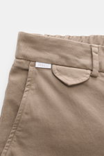 Nahaufnahme der Bündchen- und Taschendetails der taupefarbenen 04651/ A trip in a bag Baumwollhose 'Flex' mit teilelastischem Bund, französischer Tasche und kleinem Weblabel, fotografiert von schräg oben.