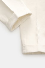 Close-up front side view of Michael Coal Chino 'Work Mc-Louis' cream pants showing twill cotton fabric with distinctive weave, firm soft feel, garment dyed, slim fit, ankle-length tapered leg, zipper and waistband button, French pockets, patch back pocket