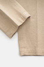 Nahaufnahme der Michael Coal Baumwollhose beige, fotografiert von schräg oben, zeigt Twill aus Baumwolle, elastische Qualität, weicher Griff, Regular Fit, sehr schmal zulaufend, Reißverschluss und Bundknopf, verlängerter Knopfriegel, französische Taschen 