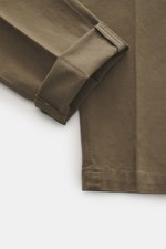 Close-up view of Michael Coal Cotton trousers olive showing folded cuff, twill made of cotton, stretch quality, soft touch, regular fit, very tapered, zipper and waistband button, extended button tab, French pockets, and piped back pockets.