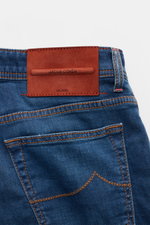 Close-up rear view of Jacob Cohen Jeans 'Bard' rauchblau showing leather patch, stitching, and back pocket details. Modern luxury with elastic cotton denim, soft touch, light used wash, slim fit, button fly, five-pocket style, coin pocket with initial, st