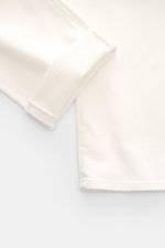Close-up top view of Moorer Jeans 'Milton' off-white showing folded cuff and hem in stretchy cotton denim with soft feel and subtle wash, regular fit, straight cut, button fly, five-pocket style, coin pocket with embroidered logo, back pockets with stitch