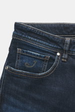 Nahaufnahme der Jacob Cohen Jeans 'Bard' navy in Slim Fit, gezeigt aus leichter Schräge von vorne oben mit sichtbar gesticktem "J" auf der Münztasche.