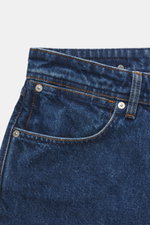 Stone Island Jeans 'Indigo Denim - Medium Grainy Wash' dark blue shown from a close-up front angle, highlighting texture, button fly, five-pocket style, and compass badge on waistband. Denim with attitude: The 'Indigo Denim - Medium Grainy Wash' jeans mad