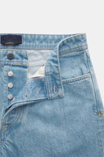 Stone Island Jeans 'Indigo Denim - Light Blue Grainy Wash' light blue jeans shown from front close-up with button fly open, subtle wash, five-pocket style, compass badge on waistband, made of pure cotton with straight cut and Straight Fit. Denim with atti