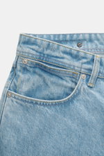 Stone Island Jeans 'Indigo Denim - Light Blue Grainy Wash' hellblau, Nahaufnahme der Fronttasche und Bund mit Kompass-Badge, Used-Waschung, gerader Schnitt.