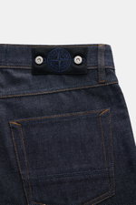Close-up rear view of Stone Island Jeans 'Indigo Denim - Raw' navy showcasing pure cotton denim, textured quality, regular fit, straight cut, button fly, five-pocket style, and signature compass badge on waistband.